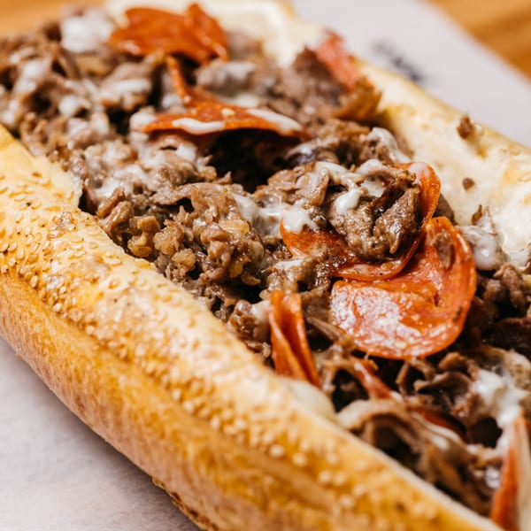 Ochinilis Steaks' cheesesteak with melted cheese, steak, and pepperoni on a sesame seed roll.